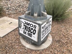 Wheat paste sign reading "Nosomos Atrisco, Est. 1692" on the base of a light pole