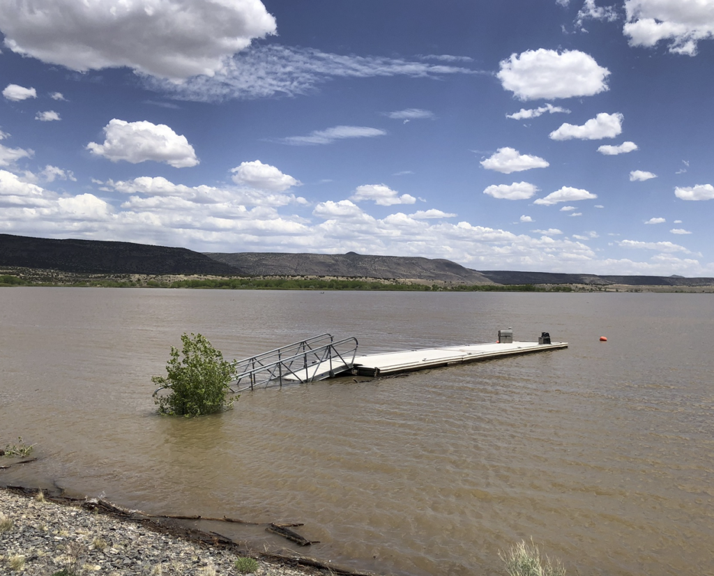 Submerged swimming dock in a reservoir with a gorgeous New Mexico sky behind it.