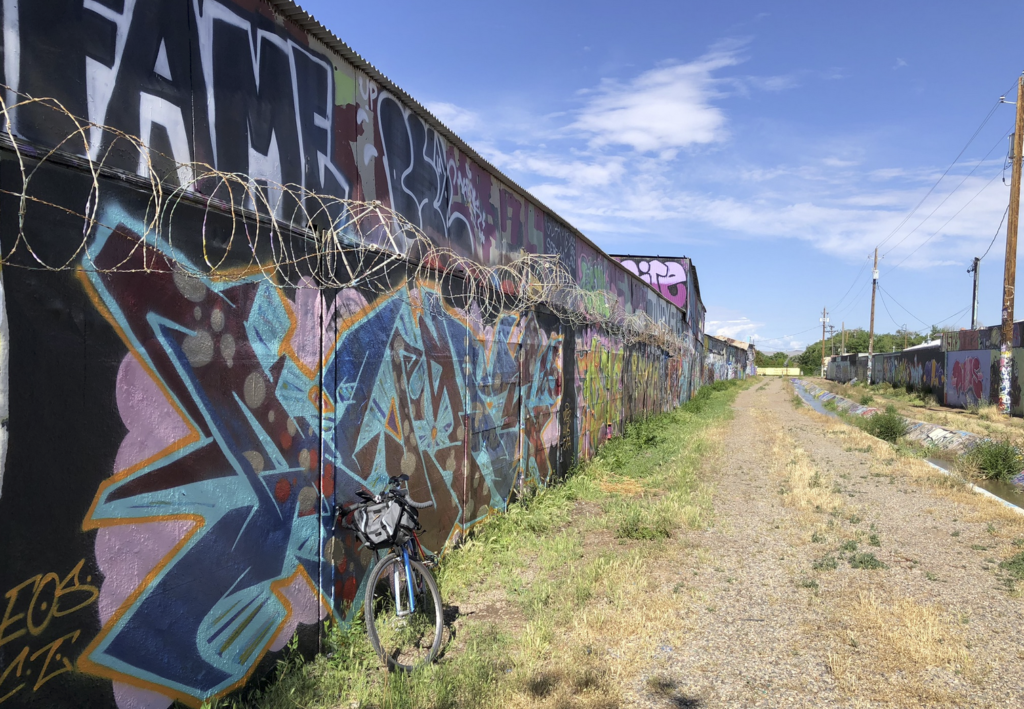 Graffiti-lined irrigation ditch corridor with bicycle.