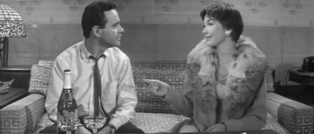 Shirley MacLaine hands a deck of cards to Jack Lemmon. In black and white.