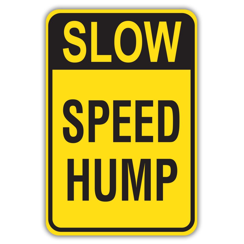 Yellow sign with black lettering reading "speed hump"