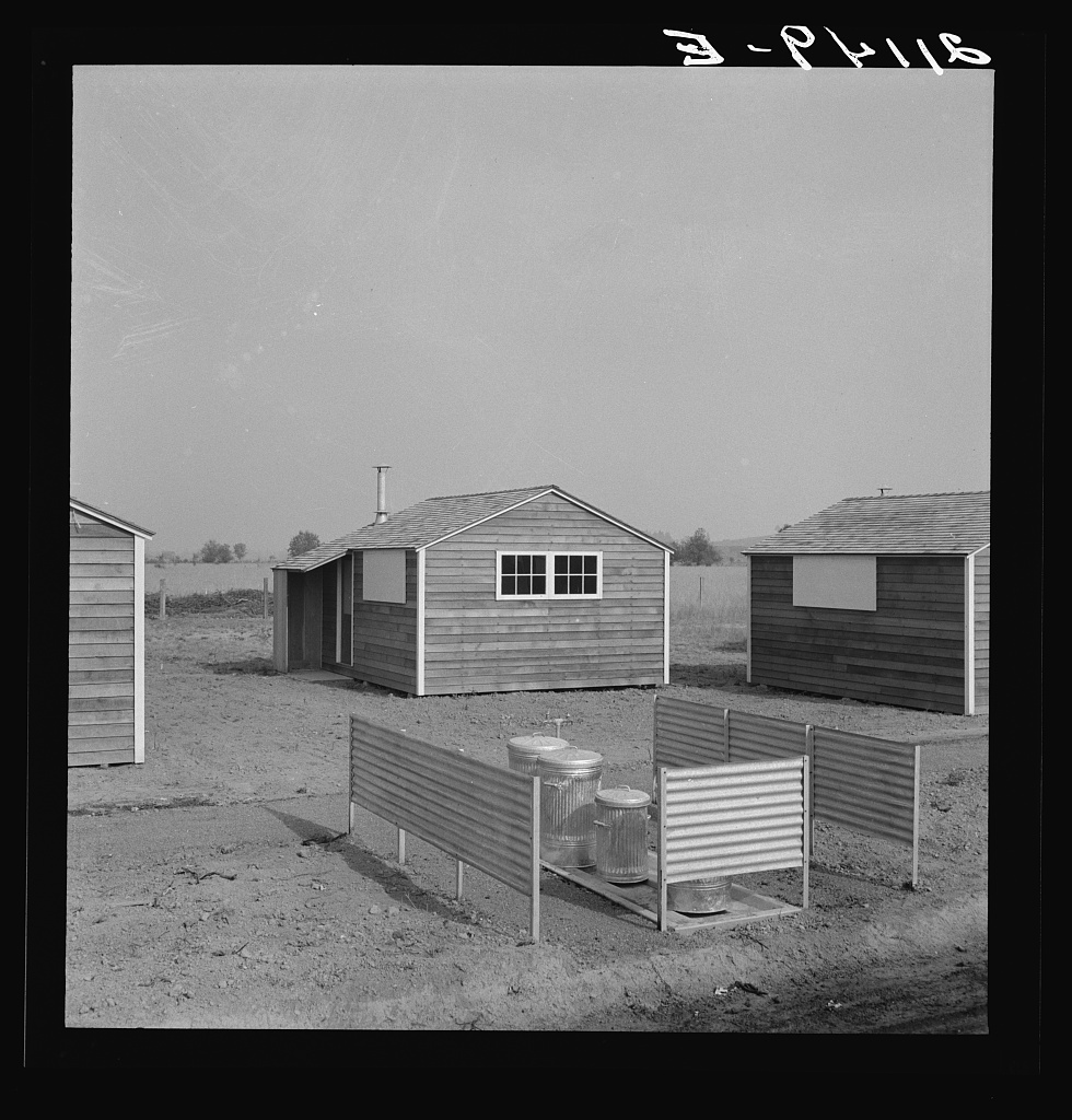Black and white photo of crisp new-looking buildings with a garbage enclousure.